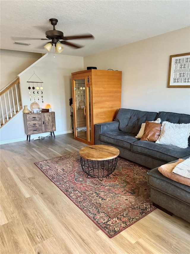 living room featuring ceiling fan, wood-type flooring, and a textured ceiling