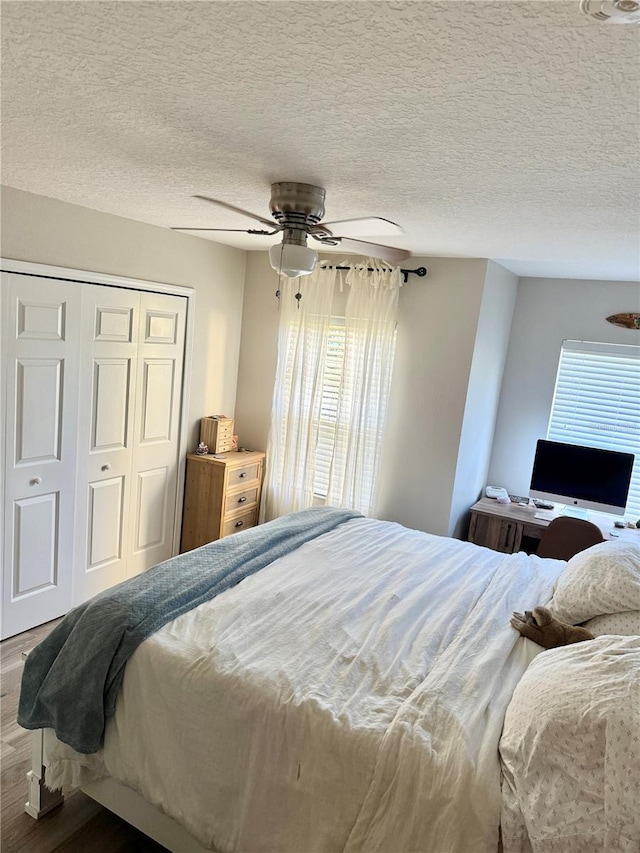 bedroom with hardwood / wood-style floors, a textured ceiling, a closet, and ceiling fan