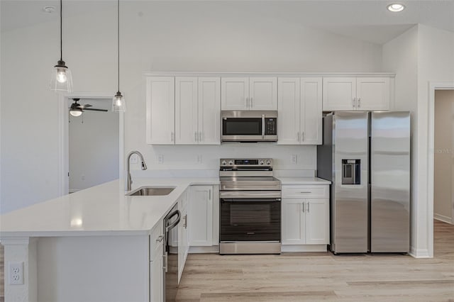 kitchen with white cabinets, decorative light fixtures, lofted ceiling, and appliances with stainless steel finishes