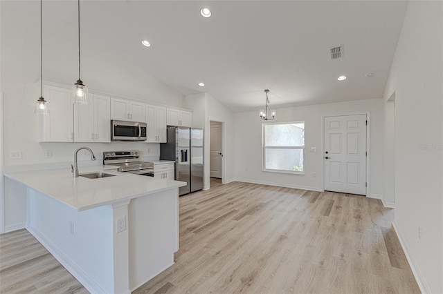 kitchen with lofted ceiling, white cabinets, appliances with stainless steel finishes, decorative light fixtures, and kitchen peninsula