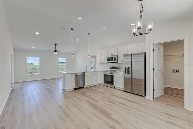 kitchen featuring lofted ceiling, ceiling fan with notable chandelier, hanging light fixtures, appliances with stainless steel finishes, and kitchen peninsula