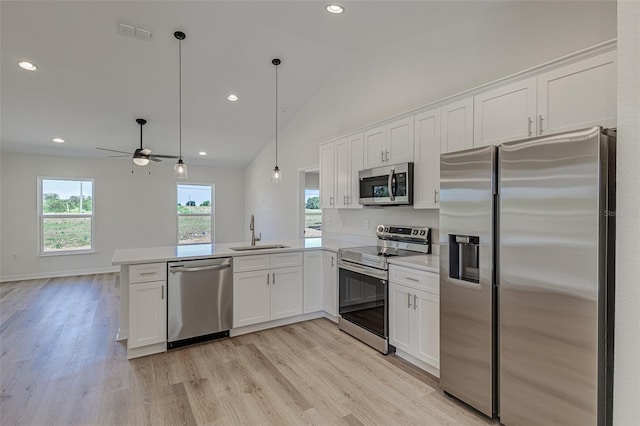 kitchen with sink, vaulted ceiling, decorative light fixtures, white cabinets, and appliances with stainless steel finishes