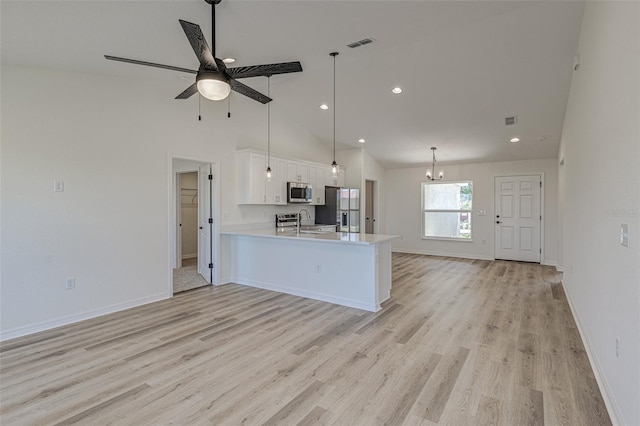 kitchen featuring kitchen peninsula, stainless steel appliances, sink, white cabinets, and hanging light fixtures