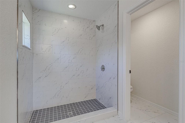 bathroom with a tile shower and toilet