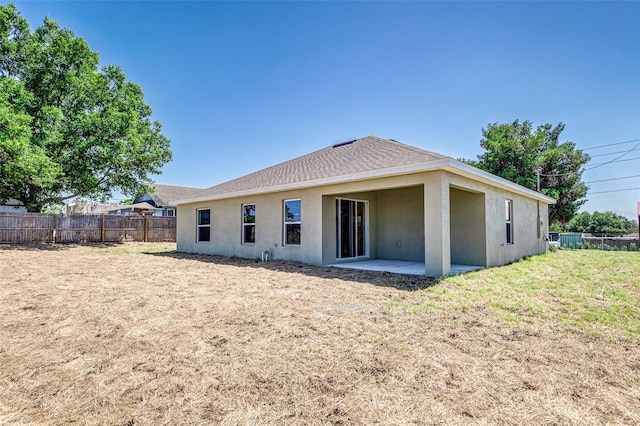 back of property with a lawn and a patio