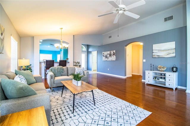 living room with dark wood-type flooring, lofted ceiling, and ceiling fan with notable chandelier