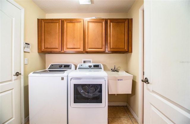 clothes washing area featuring light tile patterned flooring, cabinets, sink, and washer and dryer