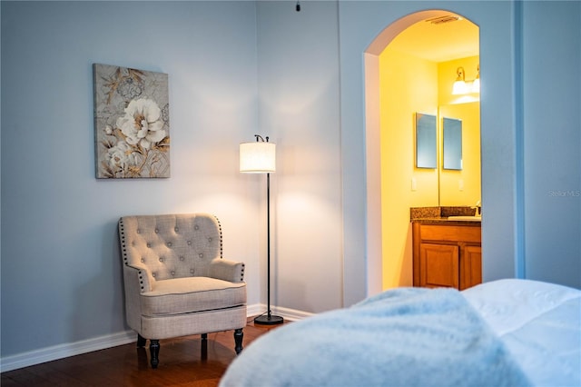 bedroom featuring dark wood-type flooring, ensuite bath, and sink