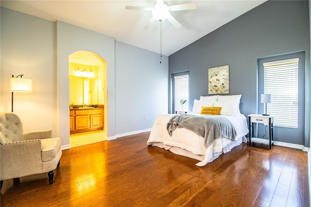 bedroom featuring wood-type flooring, vaulted ceiling, sink, and connected bathroom