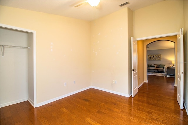 unfurnished bedroom with ceiling fan, dark hardwood / wood-style flooring, and a closet