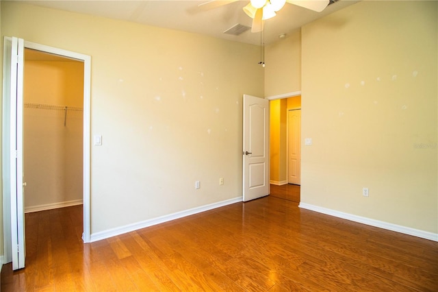 unfurnished bedroom with hardwood / wood-style floors, a walk in closet, a closet, and ceiling fan