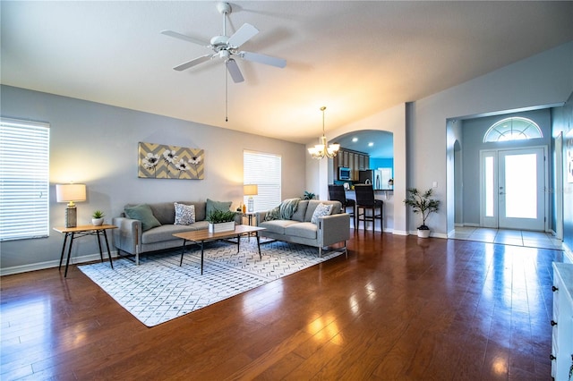 living room featuring ceiling fan with notable chandelier, dark hardwood / wood-style floors, and vaulted ceiling