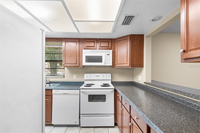 kitchen with sink, light tile patterned floors, and white appliances