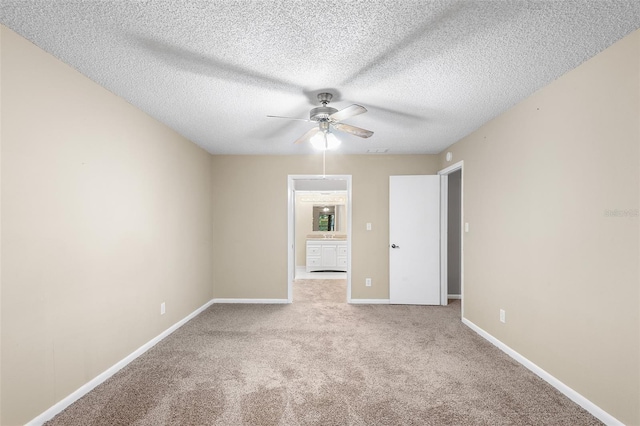 spare room with a textured ceiling, light colored carpet, and ceiling fan