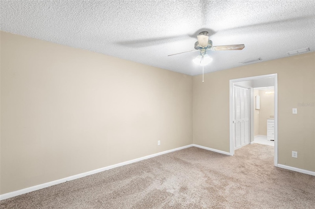 spare room featuring ceiling fan, light colored carpet, and a textured ceiling