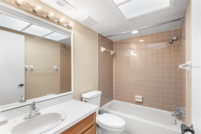 full bathroom featuring tiled shower / bath, vanity, and toilet