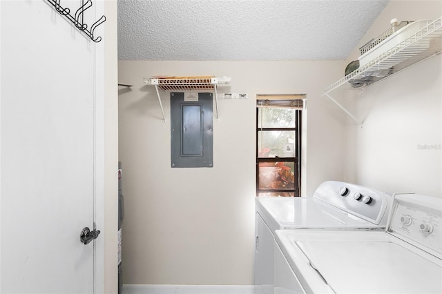 laundry room featuring electric panel, washer and dryer, and a textured ceiling