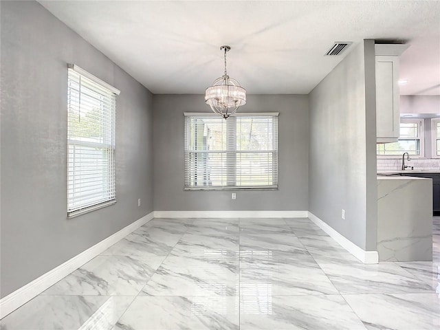 unfurnished dining area featuring an inviting chandelier, sink, and a wealth of natural light
