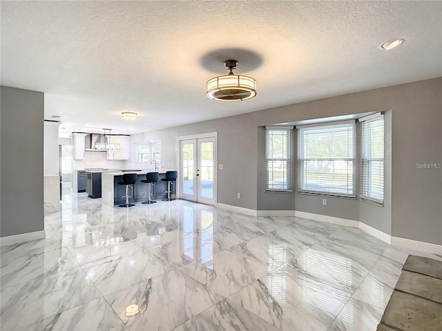 unfurnished living room featuring french doors and a textured ceiling