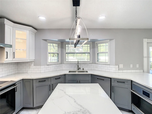kitchen with white cabinetry, black dishwasher, sink, hanging light fixtures, and stainless steel oven