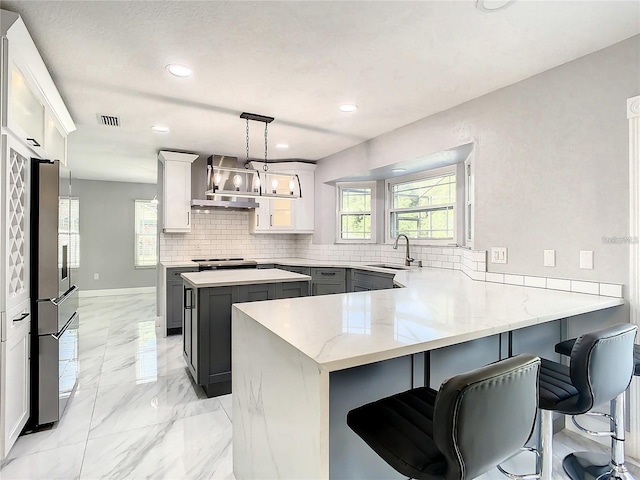 kitchen with hanging light fixtures, a center island, gray cabinets, and kitchen peninsula