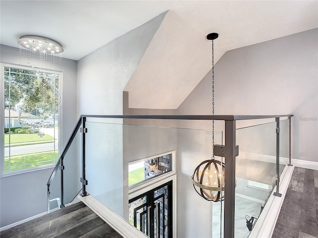 stairway with wood-type flooring, a chandelier, and vaulted ceiling