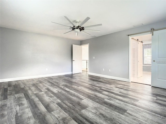 empty room with hardwood / wood-style floors, a barn door, and ceiling fan