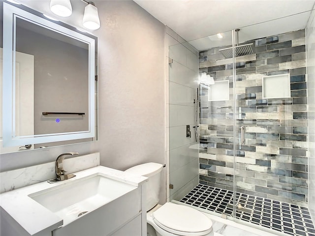 bathroom featuring vanity, a shower with door, and toilet