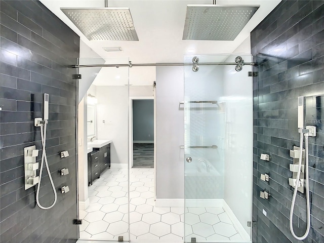 bathroom with walk in shower, tile patterned floors, vanity, and tile walls