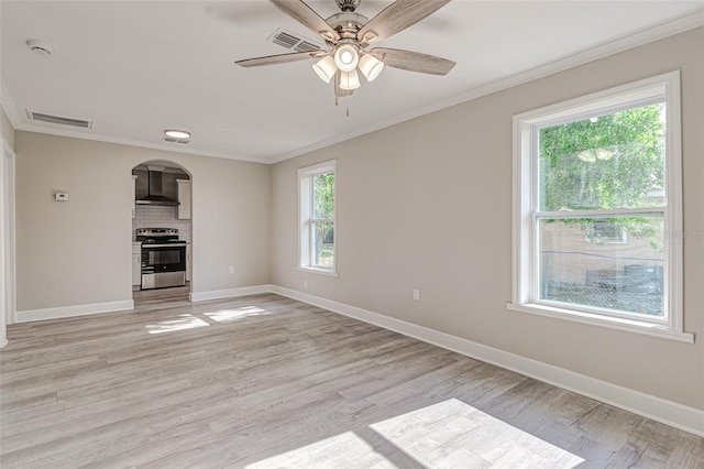 unfurnished living room featuring ceiling fan, a healthy amount of sunlight, light wood-type flooring, and crown molding