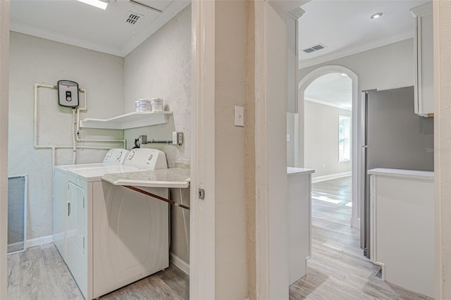 washroom featuring washing machine and clothes dryer, ornamental molding, and light wood-type flooring