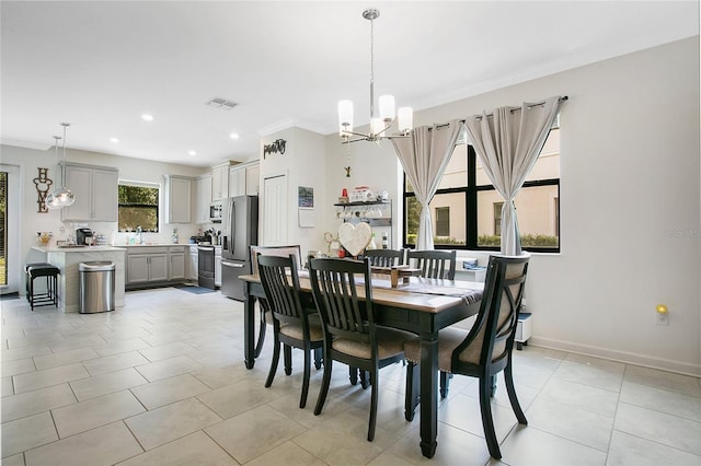 tiled dining space with a notable chandelier, ornamental molding, and sink