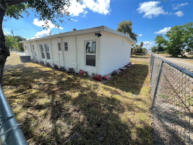 view of side of property featuring a yard and central AC