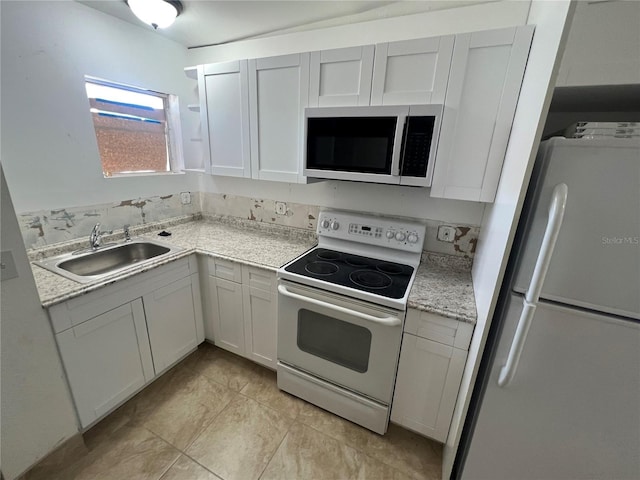 kitchen with light stone countertops, white appliances, sink, white cabinets, and light tile patterned flooring