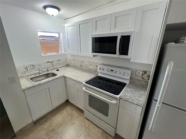 kitchen with white appliances, sink, light tile patterned flooring, light stone counters, and white cabinetry