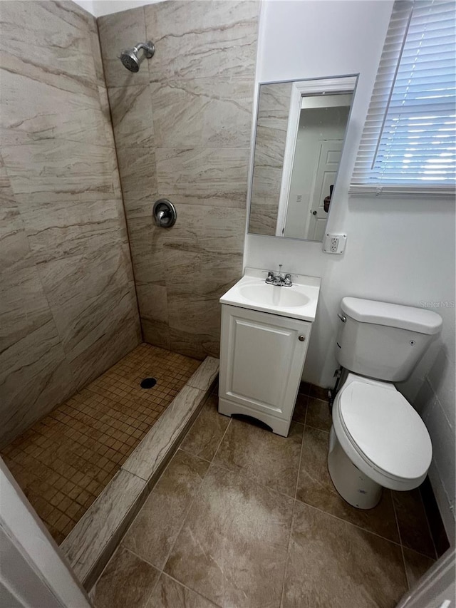 bathroom with a tile shower, vanity, and toilet