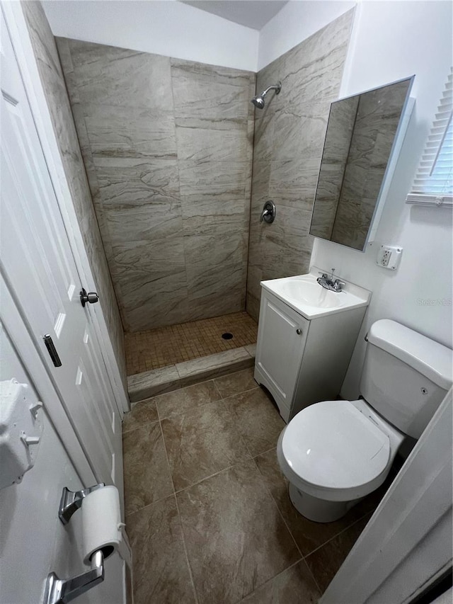 bathroom featuring toilet, vanity, and tiled shower