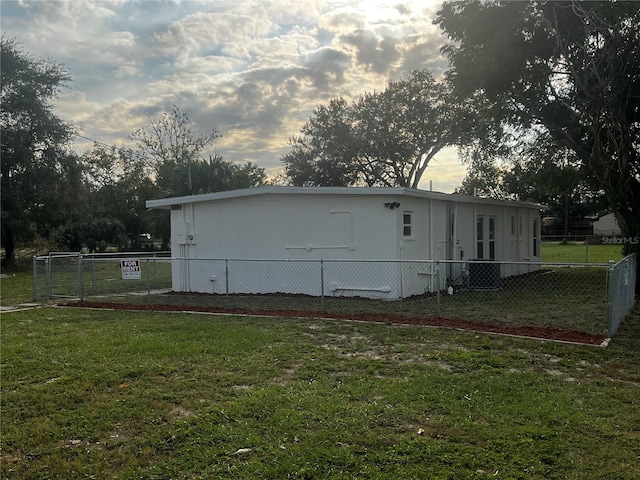 property exterior at dusk featuring a yard and cooling unit