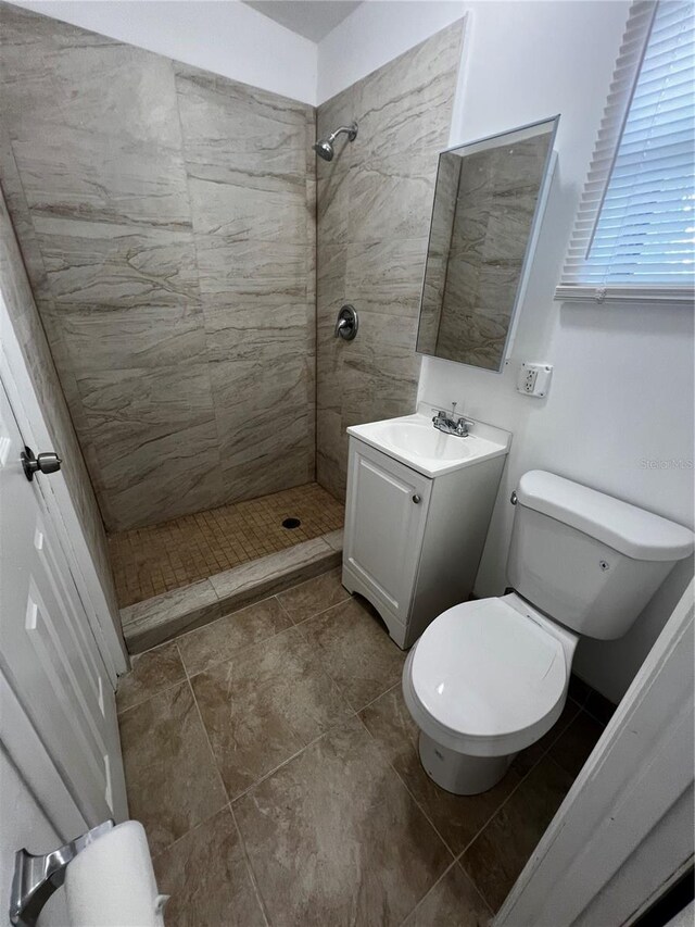 bathroom featuring tiled shower, vanity, and toilet