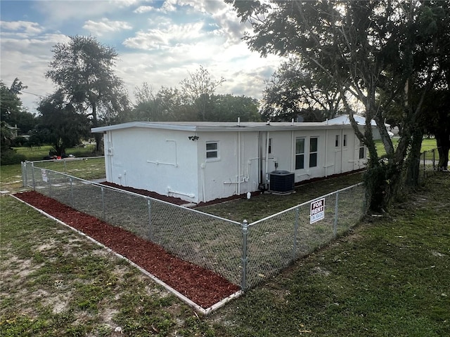 rear view of property featuring central air condition unit and a lawn