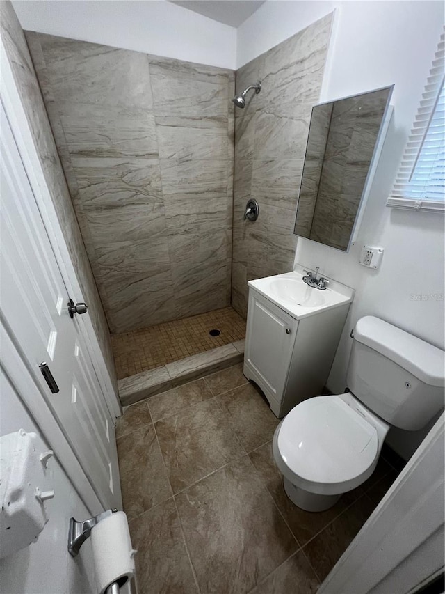 bathroom featuring vanity, toilet, and a tile shower