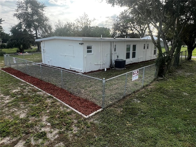 back of house with central air condition unit and a lawn