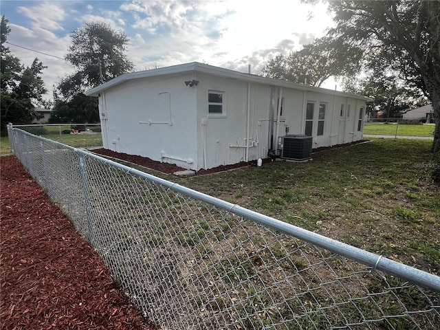 view of side of property featuring a yard and central AC unit