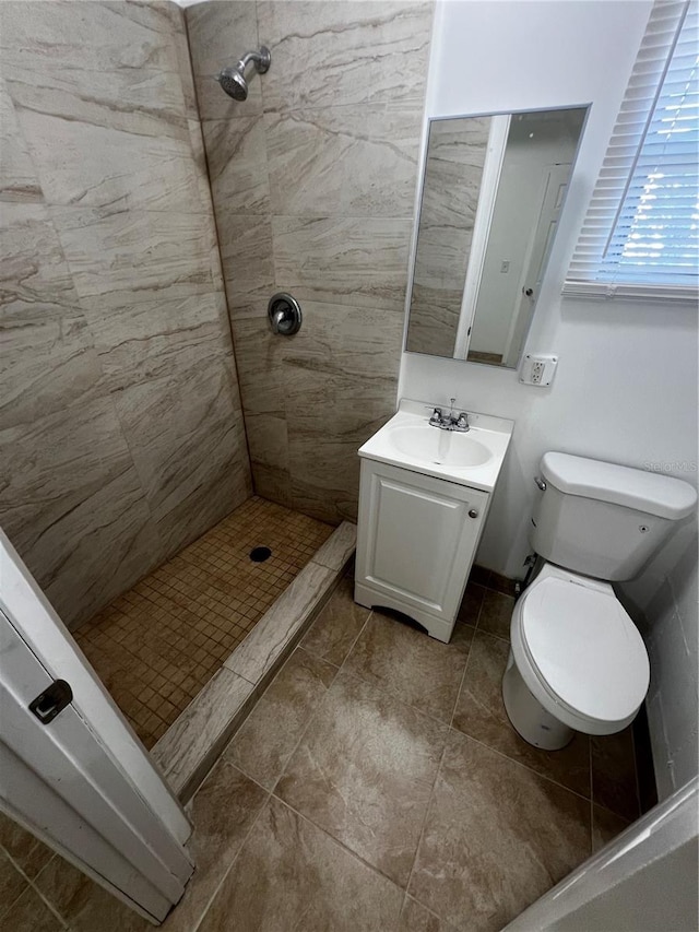 bathroom with tiled shower, vanity, and toilet