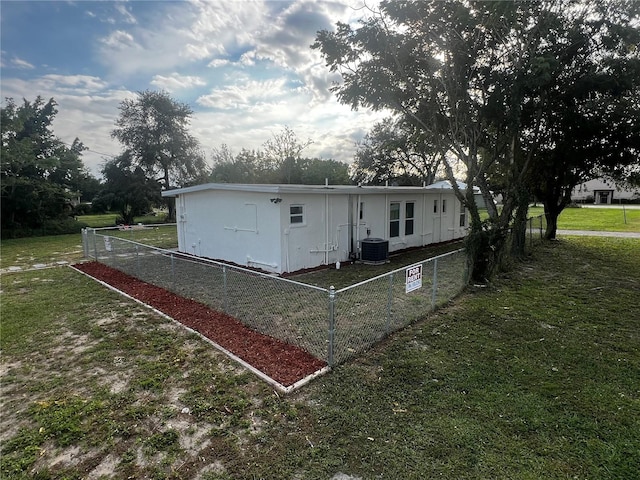 rear view of house featuring central AC unit and a lawn