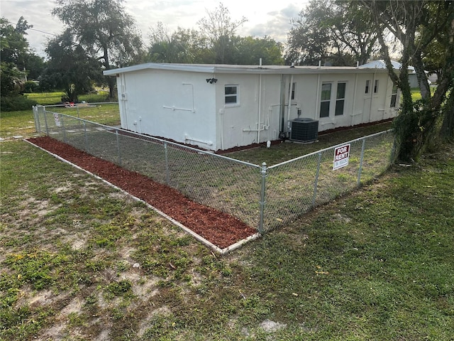 rear view of property with cooling unit and a yard