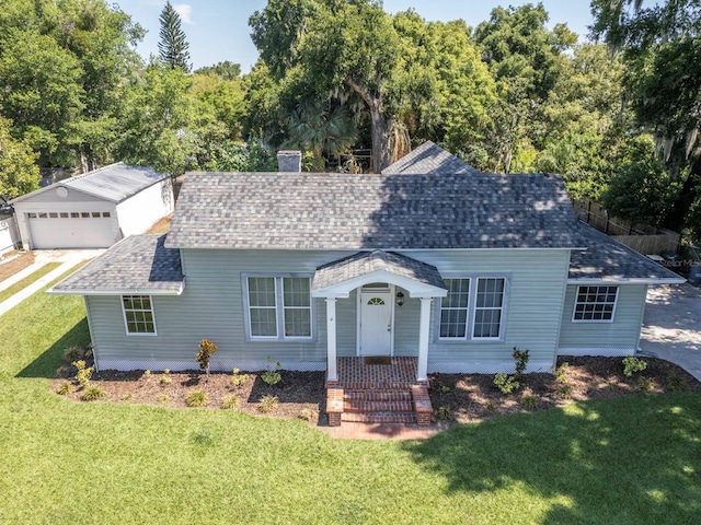 view of front of house featuring a garage, a front yard, and an outdoor structure