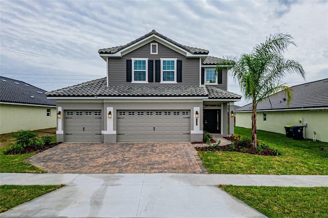 view of front facade featuring a front yard, decorative driveway, a tiled roof, and stucco siding