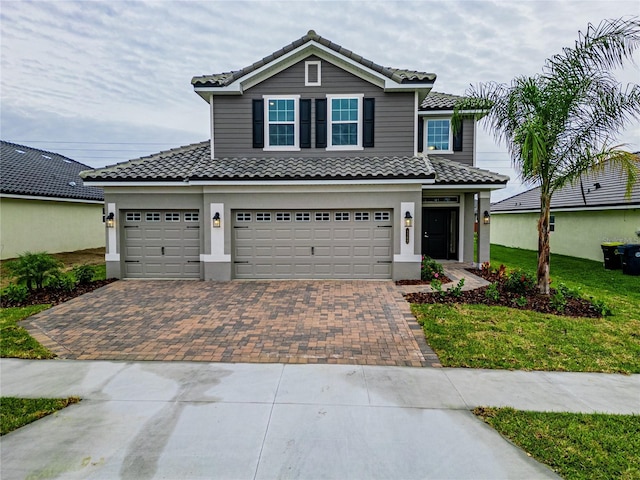 view of front facade with a tiled roof, decorative driveway, and stucco siding