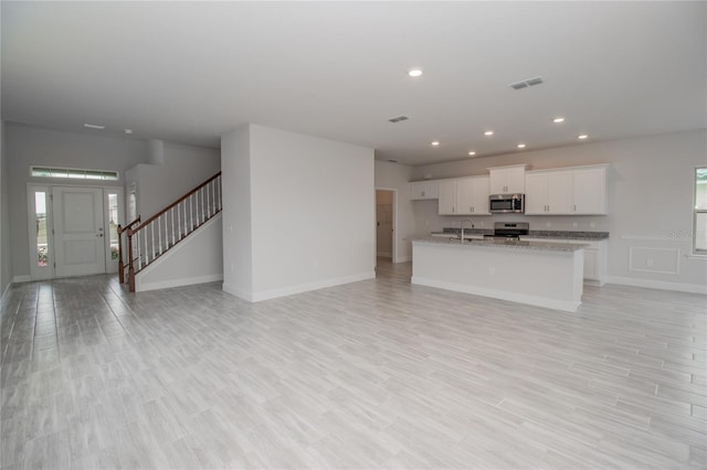 unfurnished living room featuring sink and a healthy amount of sunlight